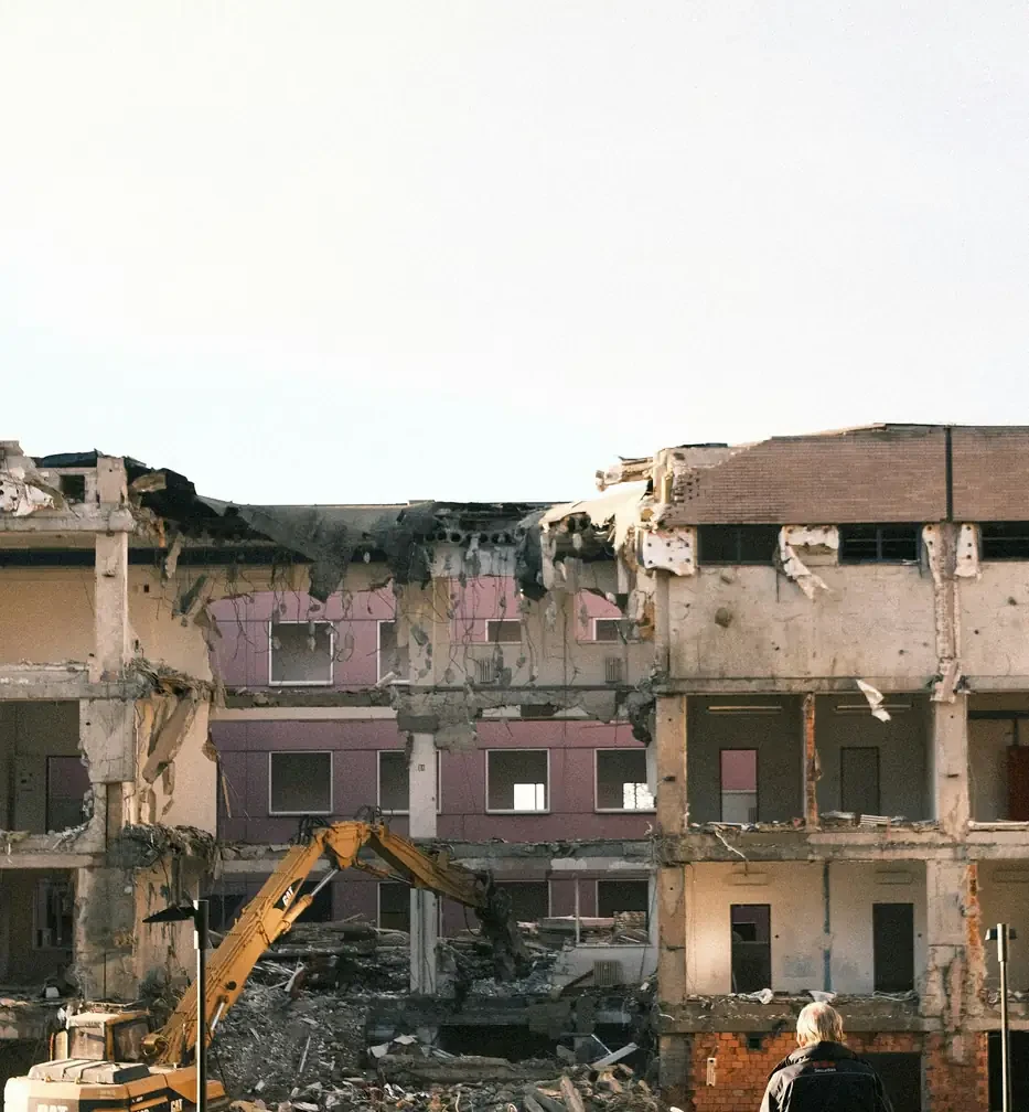 A demolition in progress seen from the street behind temporary safety fencing