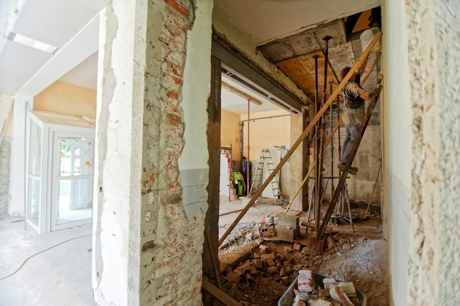 An opening formed in a wall with propping in place and a worker on a ladder alongside